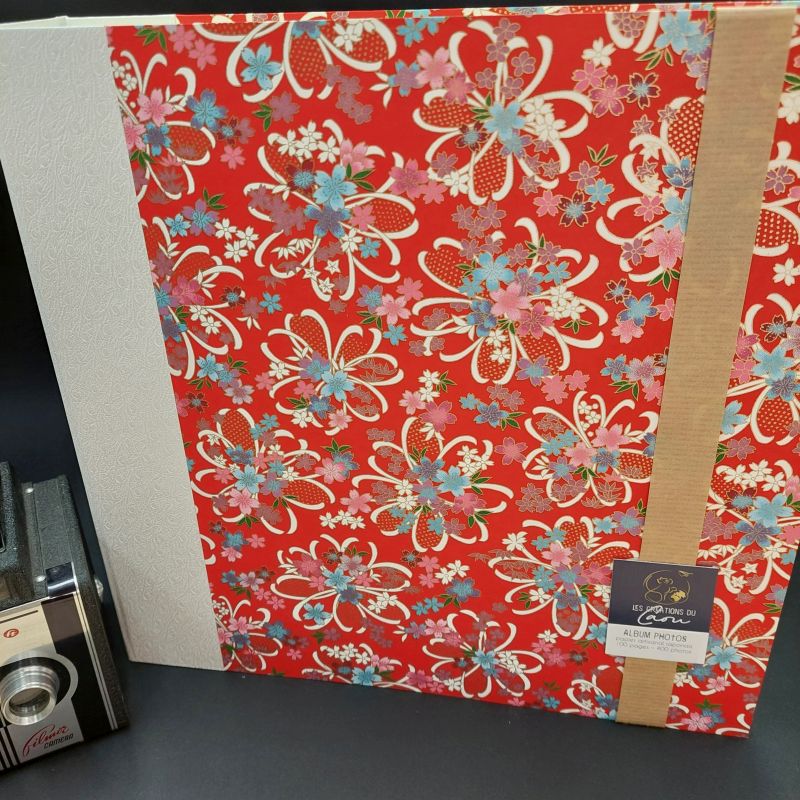 Album photos permettant d'accueillir 400 photos recouvert d'un papier japonais rouge décoré de rubans blancs et de fleurs