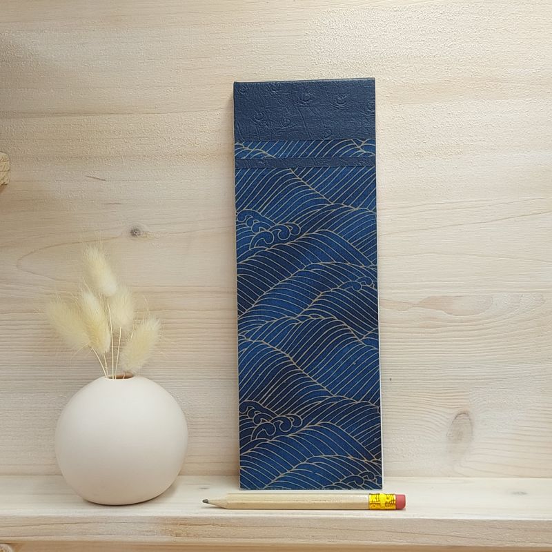 Bloc à listes recouvert de papier japonais sur fond bleu nuit avec un motif de vaque