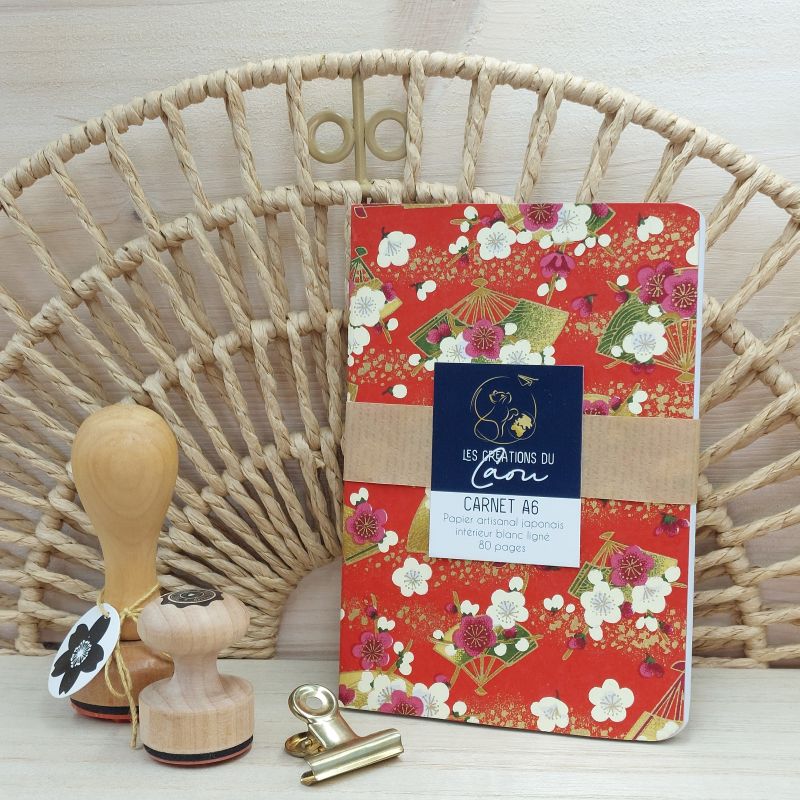 La couverture souple de ce carnet A6 80 pages est recouverte à la main d’un délicat papier artisanal japonais au motif d'éventails, dans les tons bordeaux rouge, beige et doré.